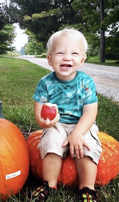 Toddler sitting on pumpkin at sage's apples in geauga county ohio