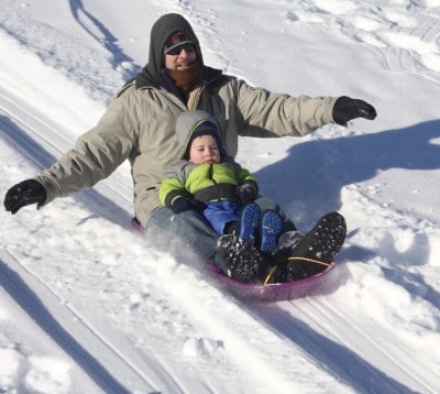 father and son sledding down hill in geauga county