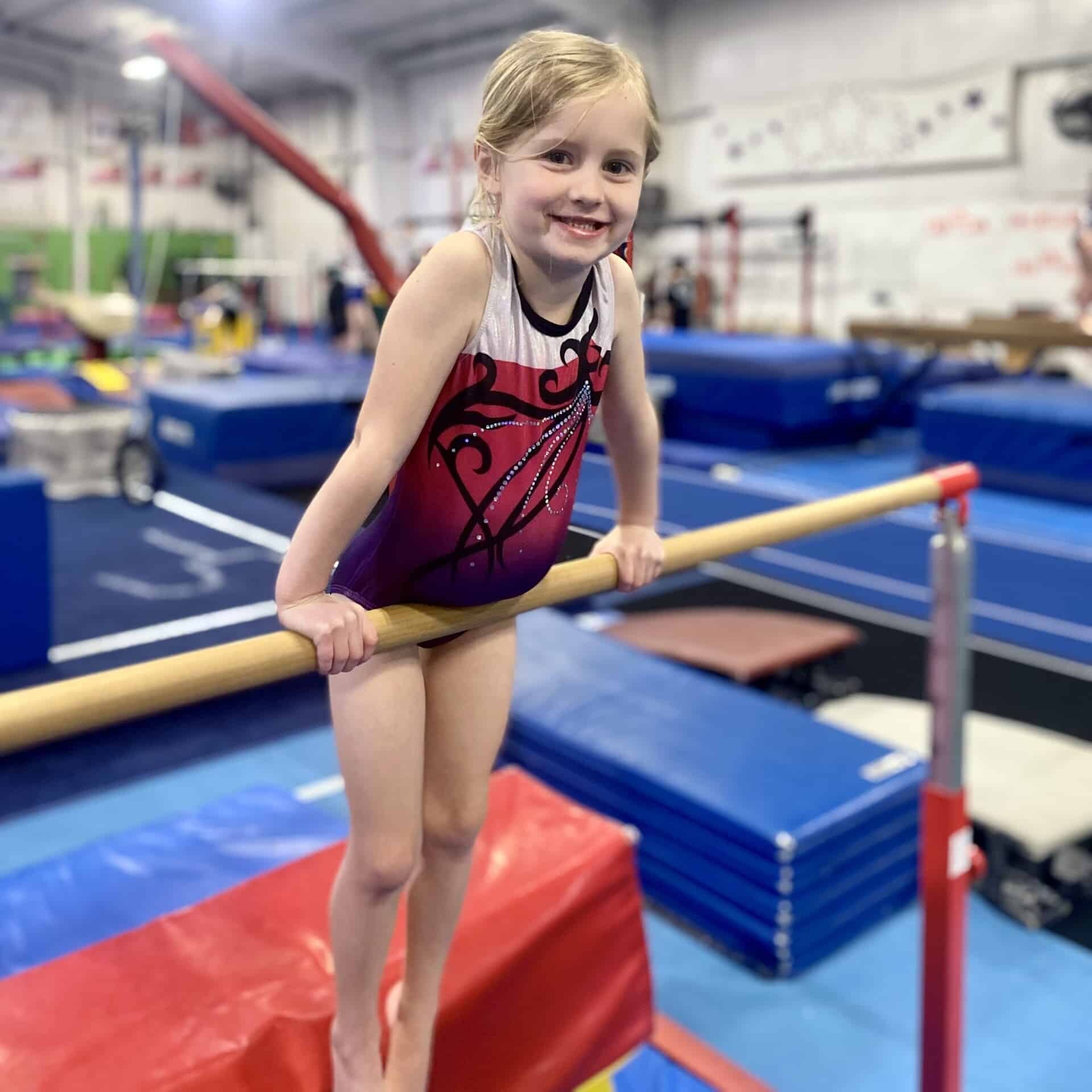 Smiling girl on bars at EmethGym girls class