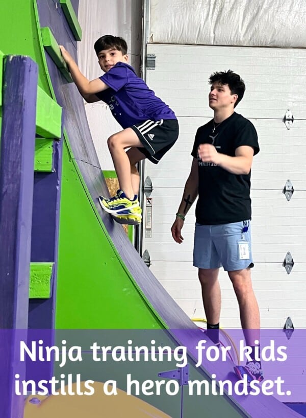 Student in ninja training class for kids with coach nearby Student in ninja training class for kids with coach nearby