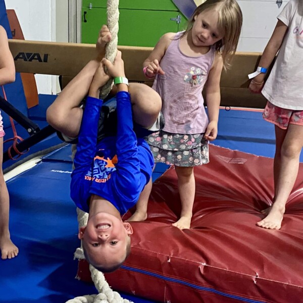 Boy hanging upside down on rope at Emeth fun camp