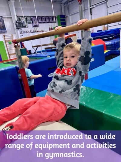 Toddler boy in gymnastics class hanging on a bar Toddler boy in gymnastics class hanging on a bar