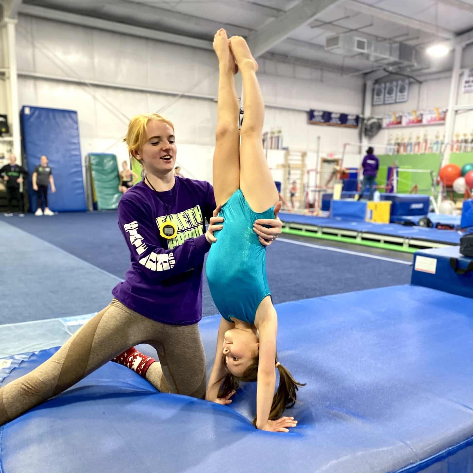 Coach spotting girl on handstand in beginning tumbling Coach spotting girl on back walkover