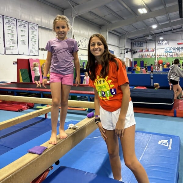Coach with child on balance beam at Emeth Summer Day Camp Coach with child on balance beam at Emeth Summer Day Camp