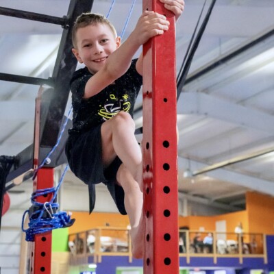 Boy climbing vertical bar in Ninja+ class Boy climbing vertical bar in Ninja+ class